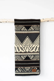 Black and cream geometric patterned blanket with leather patch, hanging on a wooden rod