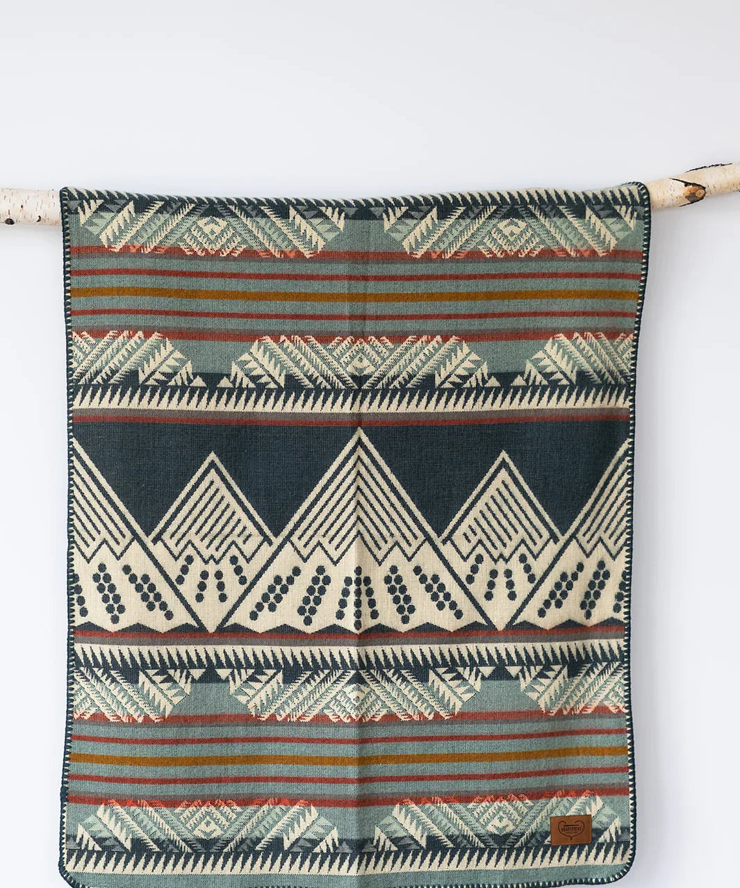 Geometric patterned throw blanket with Southwestern design hanging on a branch