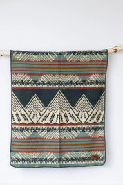 Geometric patterned throw blanket with Southwestern design hanging on a branch