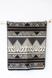 Black and cream geometric patterned blanket with mountain design hanging on wooden rod