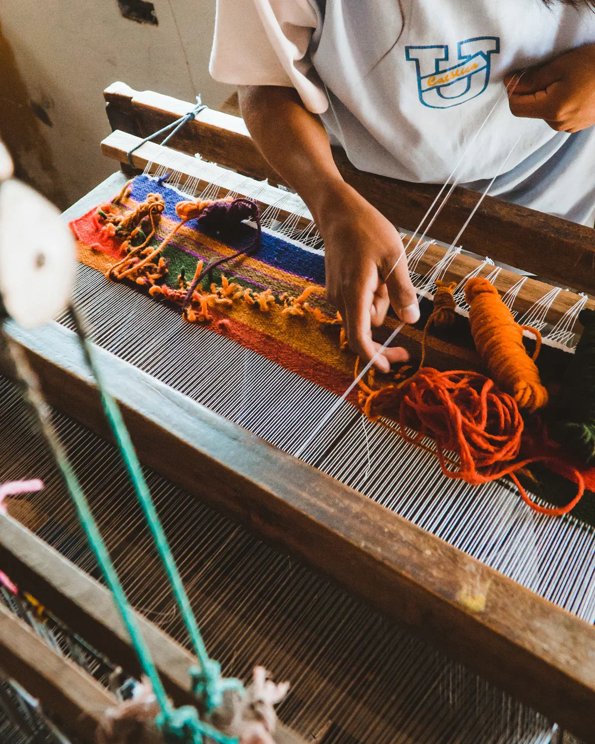 Artisan weaving colorful blanket on a loom with vibrant yarns, handmade textile craftsmanship