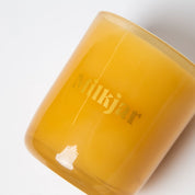 Yellow glass Milkjar candle on white background, minimalist home decor