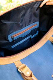 Interior of blue canvas tote bag with leather trim and multiple pockets