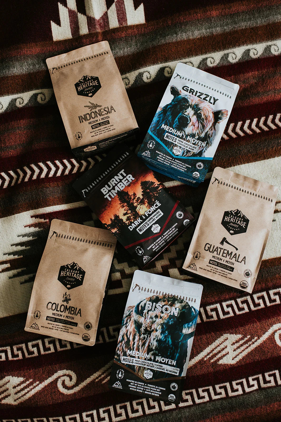 Assorted craft coffee bags including Grizzly, Bison, Indonesia, and Guatemala on a patterned blanket