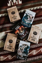 Assorted craft coffee bags including Grizzly, Bison, Indonesia, and Guatemala on a patterned blanket